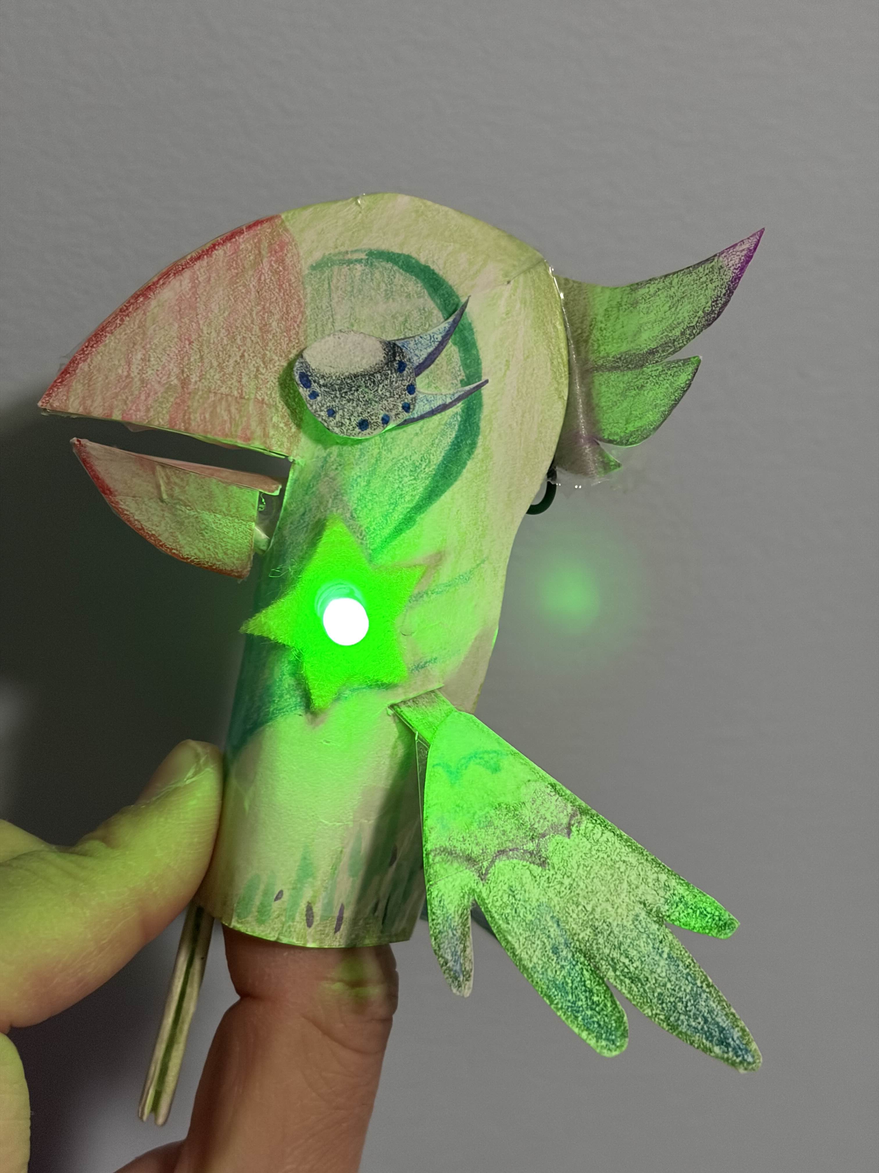 Bird puppet with a light that is turned on. The beak opens and the wing flaps
              as the bottom bar is tugged down. This also completes the circuit.